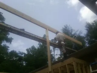 Carpenter setting a ridge beam over a new addition frame — Ice Dam Removal by Roofing Brothers in Arbon