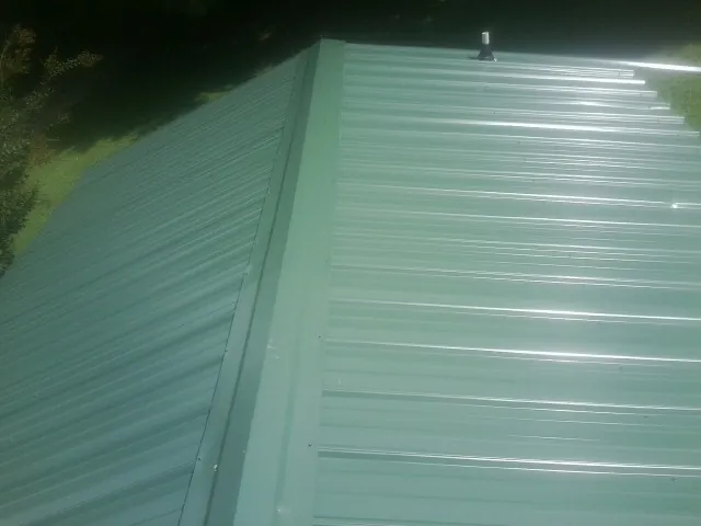 New green metal panels meeting at the ridge of a roof — Flat Roof Repair work by our crew in Arbon
