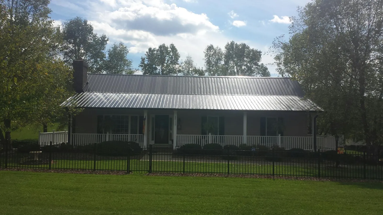 Gray metal roof on a brick ranch with a full width front porch — Gutter Guard Installation work by our crew in Arbon
