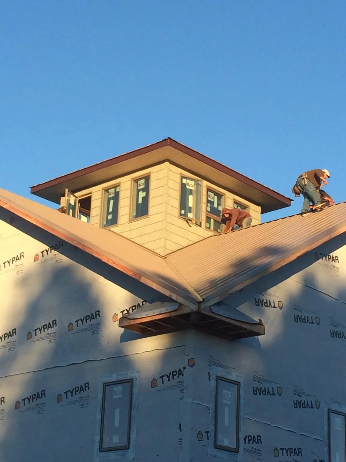 Roofers working around a rooftop cupola on a new metal roof at sunset — Roof Waterproofing in Arbon by Roofing Brothers